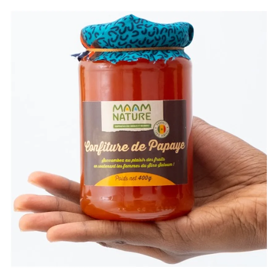 Un pot de confiture de papaye Maam Nature tenu dans une main ouverte
